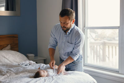 Young man looking away while sitting on bed