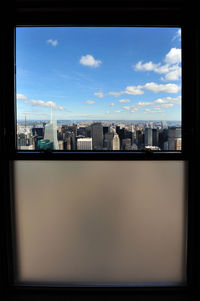 Buildings against sky seen through glass window