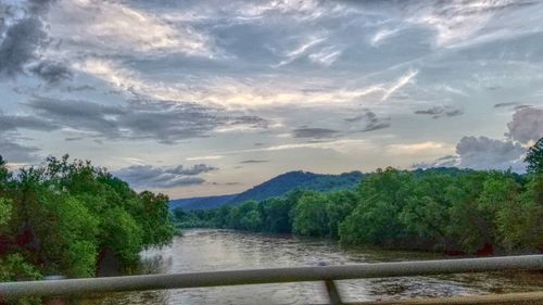 Scenic view of river by mountains against sky