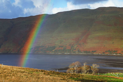 Scenic view of rainbow over mountain against sky