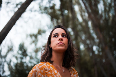 Portrait of young woman against trees