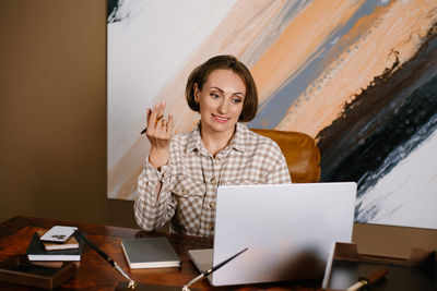 Portrait of young woman using laptop at office