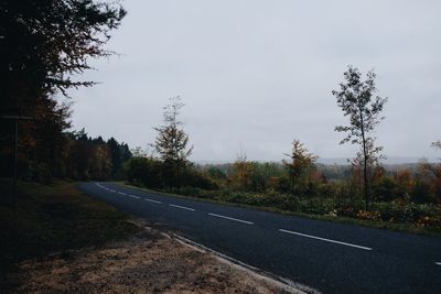 Road by trees against sky