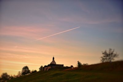 Built structure on landscape against sky during sunset