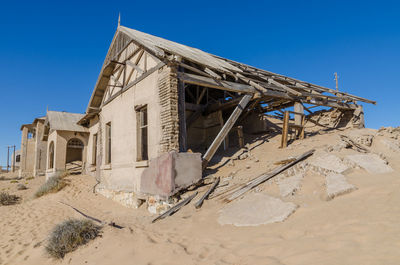 Abandoned building in desert against clear sky at ghost town kolmanskop, namibia