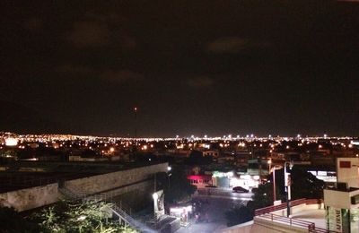 High angle view of illuminated cityscape against sky at night