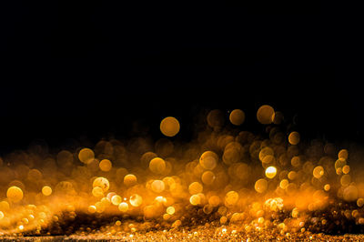 Defocused image of illuminated lights against sky at night