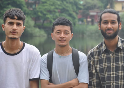 Closeup of three male friends looking at camera, posing for photo beside the lake