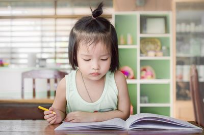 Cute girl studying while sitting at table