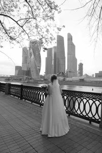 Rear view of bride standing against buildings in city