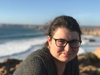 Portrait of young woman standing by sea