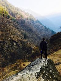 Rear view of man standing on mountain against sky