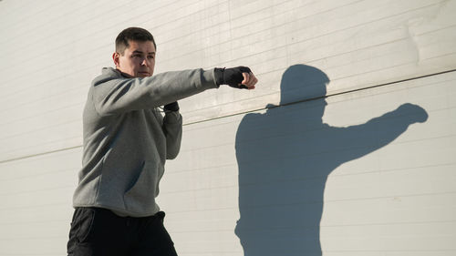 Side view of man standing against wall