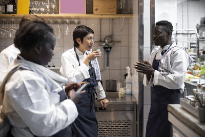 Multiracial chefs talking during break in commercial kitchen