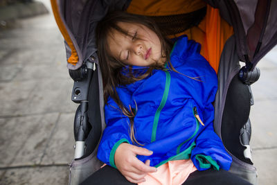 Cute girl sleeping in baby stroller on footpath