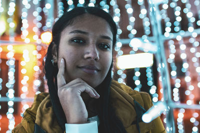 Portrait of woman standing against illuminated lights