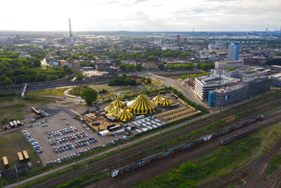 Aerial view of cityscape with contemporary buildings and circus tents placed near road on sunny day in germany