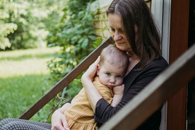 Mother embracing baby while sitting outdoors