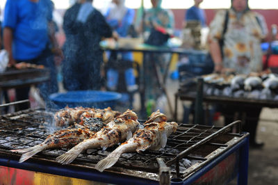 Fish grilling on barbecue at market stall