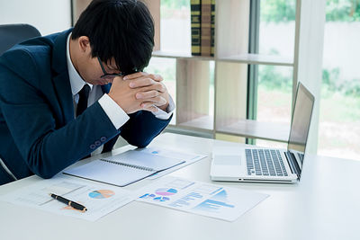 Tensed businessman using laptop in office