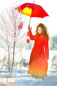 Girl with a red umbrella in a snowy field