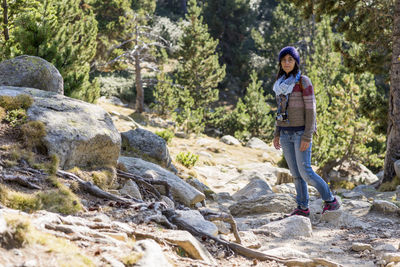 Young woman standing on rock against trees