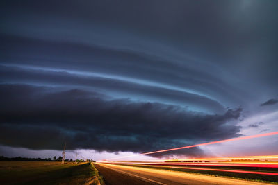 Light trails on road against sky at night