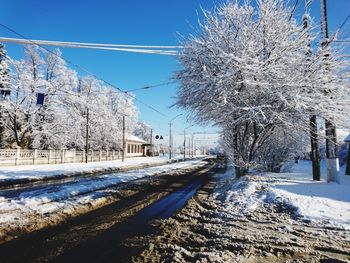 Snow covered road by trees against sky