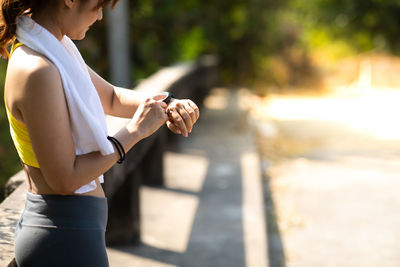 Midsection of woman using mobile phone in city