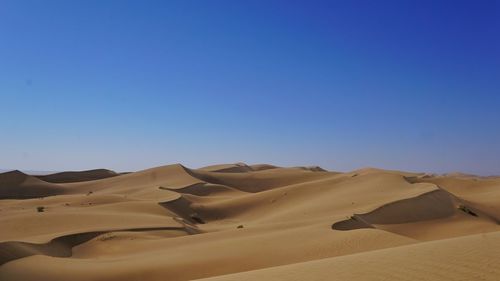 Scenic view of desert against clear blue sky