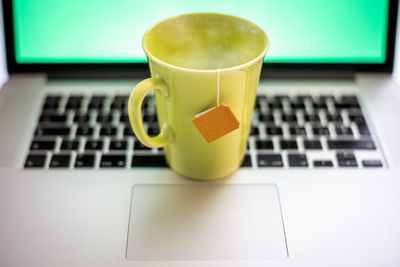 Cup of hot beverage on laptop green screen in background. steaming mug on computer. smart working