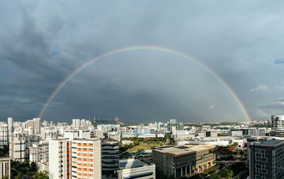 Rainbow over buildings in city against sky