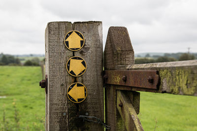 Close-up of direction arrows on field against sky