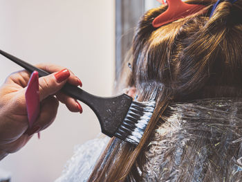 Cropped hand of hairdresser dyeing hair at salon