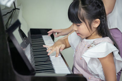 Rear view of girl playing piano
