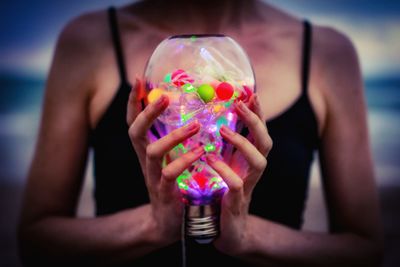 Midsection of woman holding colorful bulb