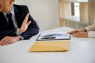 Midsection of man giving money to businessman in office