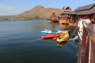 Boat moored on lake by buildings against sky