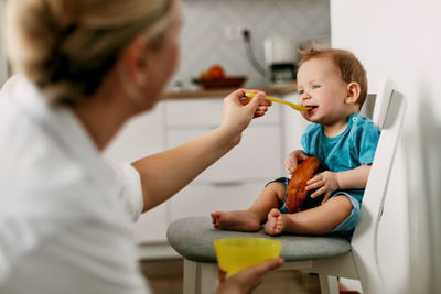 Mother feeding son at home