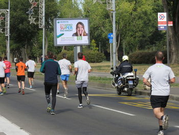 Rear view of people walking on road in city