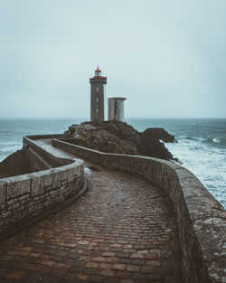 Lighthouse by sea against sky