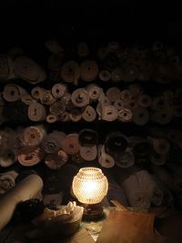 Close-up of illuminated lamp on table against rolled up fabrics at store