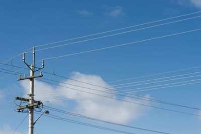 Low angle view of electricity pylon against blue sky