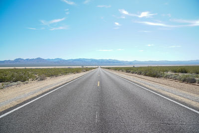 Road amidst field against sky