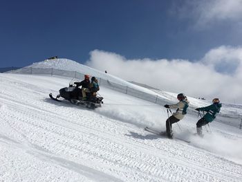 People snowmobiling and skiing on mountain