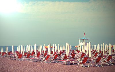 Deck chairs on beach against sky