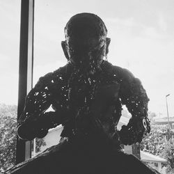 Rear view of man standing by sculpture against sky