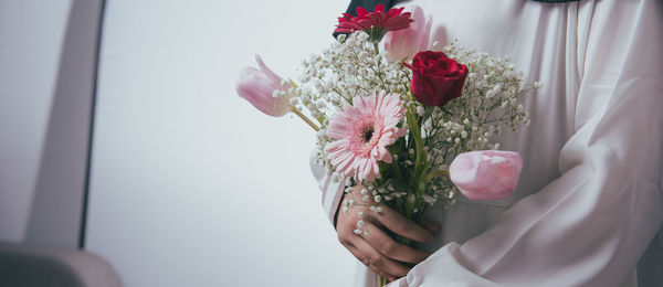 Close-up of hand holding pink rose flower