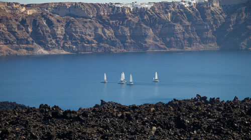 Steep cliffs of santorini. sailboats in the sea.