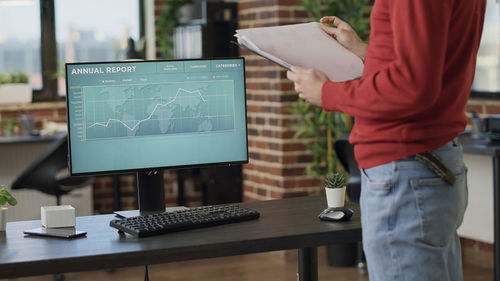 Midsection of businessman holding document in office